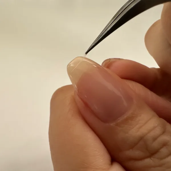 硬化前のジェルについたほこりをピンセットで取るところ